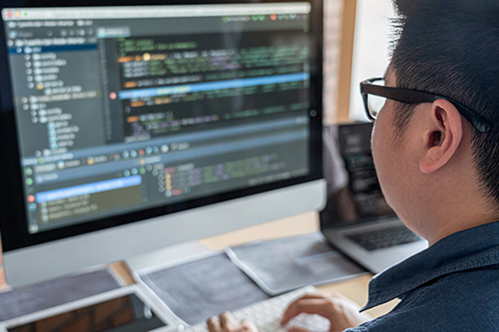 man writing code on his computer